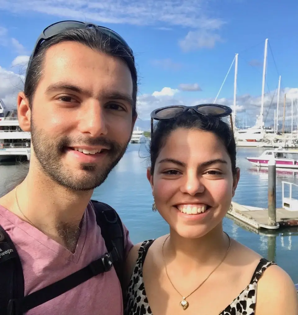 A smiling couple stands at a marina on a sunny day, symbolizing the freedom and lifestyle possible through Australian Investment Education.